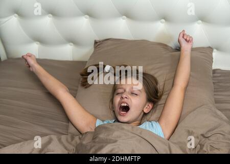 Girl with dark hair woke up in bed and yawns. high quality Stock Photo