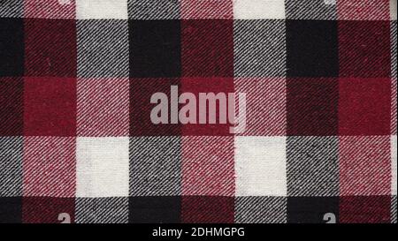 Texture of a woolen red-black-white plaid in a cage, close-up of fabric, textile winter background.Tartan fabric.Checkered pattern. Stock Photo