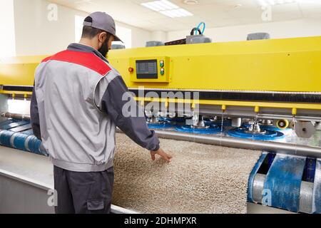 Man operating carpet automatic washing machine in professional laundry service Stock Photo