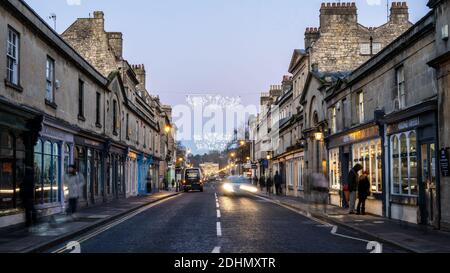 Shoppers browse in shop windows under Christmas decorations on Bath's Georgian Pulteney Bridge. Stock Photo