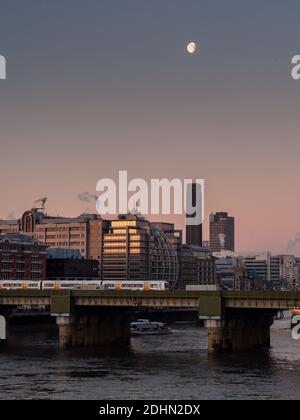 London, England, UK - January 4, 2010: A Thames Clipper and SouthEastern railway train take commuters past office blocks on the River Thames in centra Stock Photo