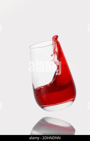Red cocktail splashes in a glass on a white background Stock Photo