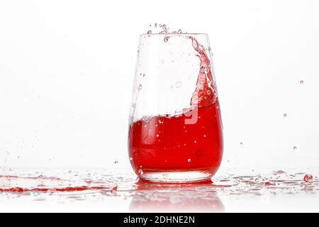 Red cocktail splashes in a glass on a white background Stock Photo