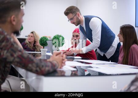 Business coach. Young man giving advices for small group of startup managers, explaining them how to grow their business Stock Photo