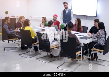 Business coach. Young man giving advices for small group of startup managers, explaining them how to grow their business Stock Photo