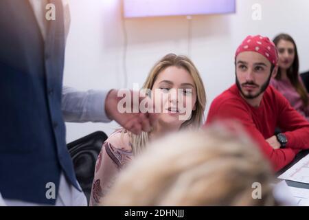 Business coach. Young man giving advices for small group of startup managers, explaining them how to grow their business Stock Photo