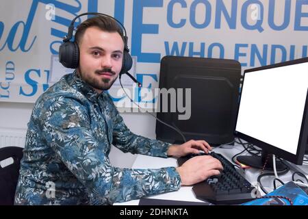 Smiling friendly helpline technical support agent with hands-free headset at call centre Stock Photo