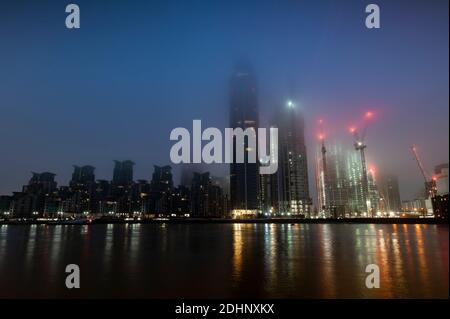 Blue photo dawn photo of london skyline in fog over River Thames St Georges Wharf and construction cranes Stock Photo