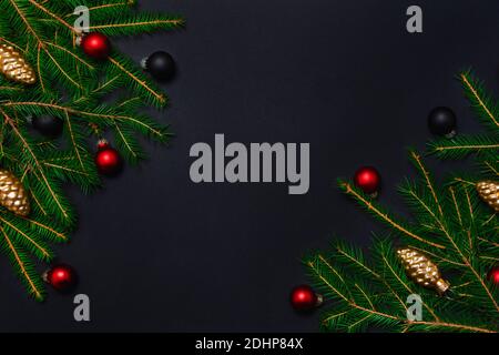 Christmas frame with fresh fir tree branches, balls and pine cones on black background. Dark holiday banner concept. Flat lay top view with copy space Stock Photo