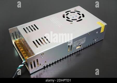 Inexpensive 14 Volt DC switching power supply on black desk Stock Photo