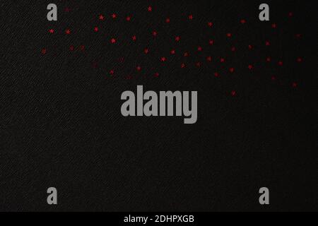 Red shiny stars on crepe paper with diagonal markings and a space for text. Black diagonal pattern for your creativity. Black pattern with shiny red s Stock Photo