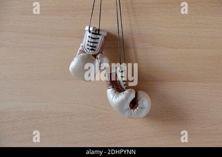 Old leather Boxing gloves hanging on a wooden wall with space for text. Stock Photo
