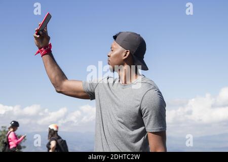 side view of one athletic african american young man from side view casual dressed with black cap using smartphone rise hand looking for reception in Stock Photo