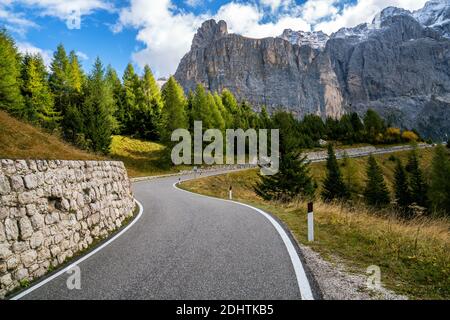 Beautiful mountain road with trees, forest and mountains in the backgrounds. Taken at state highway road in Passo Gardena, Sella mountain group of Stock Photo