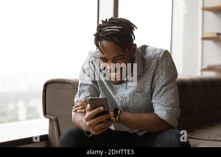 Smiling biracial man have fun using smartphone Stock Photo