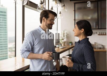 Smiling multiracial colleagues talk in office kitchen Stock Photo