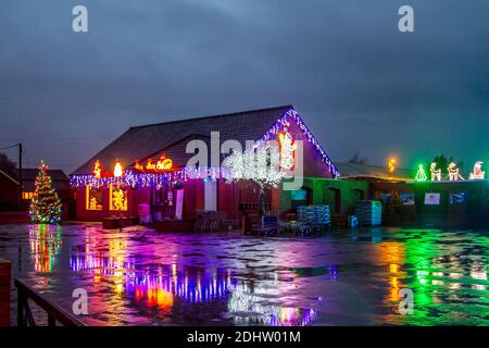 Southport, Merseyside. UK Weather: 12 Dec 2020; Garden Centre Christmas lights reflected in puddles at dawn. Overnight rain is to be followed by strong gale-force winds and further heavy prolonged rainfall in the north-west. Stock Photo