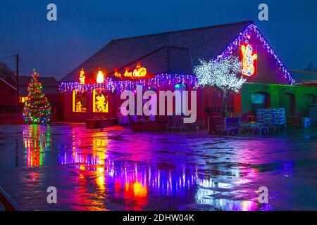 Southport, Merseyside. UK Weather: 12 Dec 2020; Garden Centre Christmas lights reflected in puddles at dawn. Overnight rain is to be followed by strong gale-force winds and further heavy prolonged rainfall in the north-west. Stock Photo