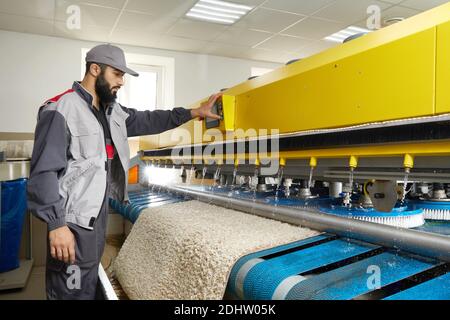 Man operating carpet automatic washing machine in professional laundry service Stock Photo