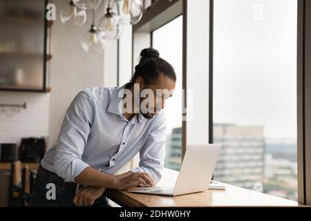 Serious biracial man work on computer at workplace Stock Photo