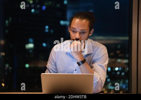 Serious biracial male employee work in office late Stock Photo
