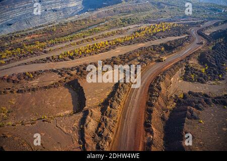 Huge mounds of waste iron ore near the quarry. Belaz trucks driving in mining factory, mine quarry in Ukraine Stock Photo