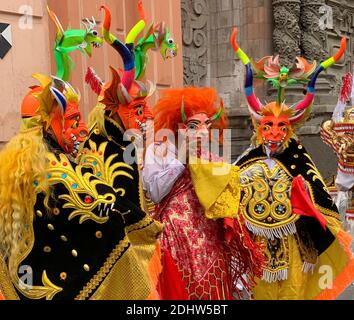 Fun holiday carnival colorful costumes of monsters in Lima, Peru, South America. Peruvian men in traditional costume with wooden demon mask Stock Photo