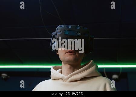 Man using virtual reality headset in dark room of vr gaming club. Concept of virtual simulation, gaming, internet of things. Stock Photo