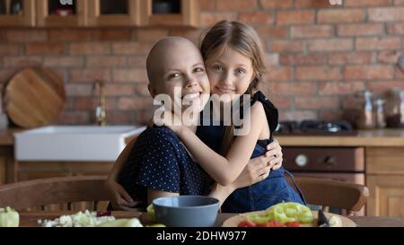 Head shot portrait smiling sick mother and daughter in kitchen Stock Photo
