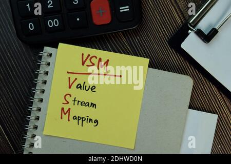 VSM - Value Stream Mapping write on sticky notes isolated on Wooden Table. Stock Photo