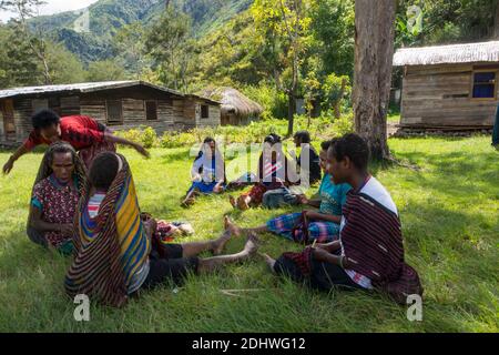 A group of women sitting on the ground and socialising in a Dani village in the Baliem Valley, West Papua, Indonesia Stock Photo