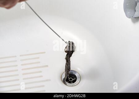 https://l450v.alamy.com/450v/2dhwg2b/clogged-drain-in-the-bathroom-a-plumber-pulls-out-a-clot-of-dirt-with-a-tool-2dhwg2b.jpg