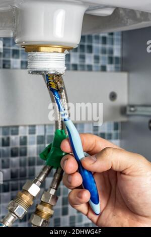 the plumber is cleaning the siphon of the washbasin in the bathroom. Stock Photo