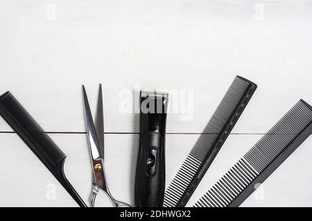 Combs, scissors, electric clipper and hairdressing tools in a beauty salon desktop on a white wooden background, top view space for text Stock Photo