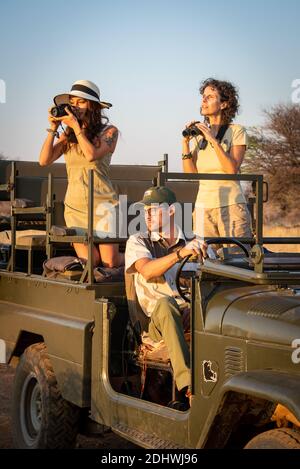 Brunettes use camera and binoculars in jeep Stock Photo - Alamy