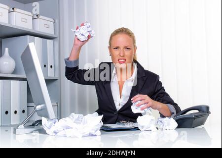 Eine Frau im Büro mit Papierknäuel. Ärger, Stress und Frust am Arbeitsplatz