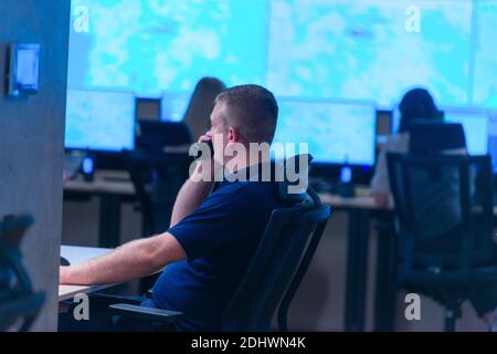 Side view of security system operator using walkie-talkie while looking at CCTV footage Stock Photo