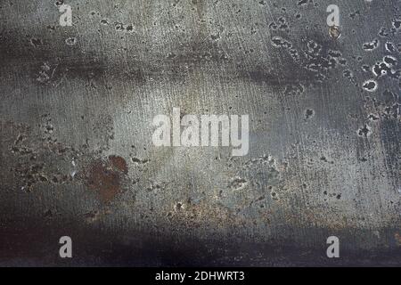 Abstract landscape of peeling grey paint on a metal plate. Rusty and stained metal surface with weld burns and scratches and stains. Artistic texture. Stock Photo