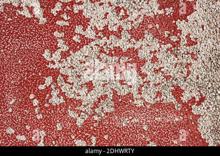 Background texture with red paint peeling and separating from an earlier paint layer leaving the original white stone to bring to light. Stock Photo