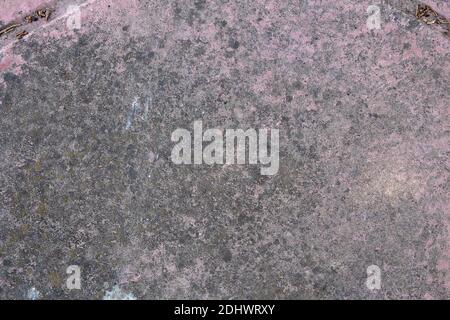 Pink stone floor with gray damp spots,  white paint splatters, and traces of seeds in diagonal crevices. Rough textured background. Stock Photo