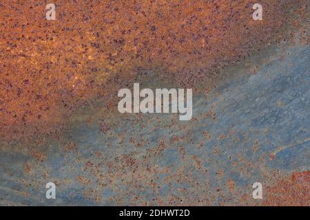 Abstract landscape of blue peeling paint on a rusty metal surface with weld burns. Artistic texture background. Stock Photo