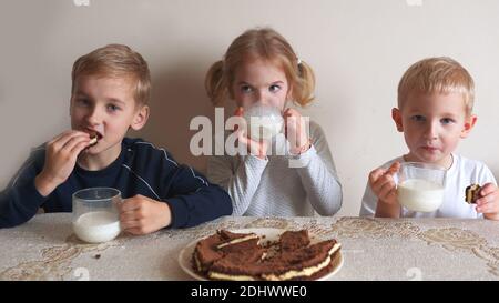 Children at the table eat milk and cookies. Stock Photo