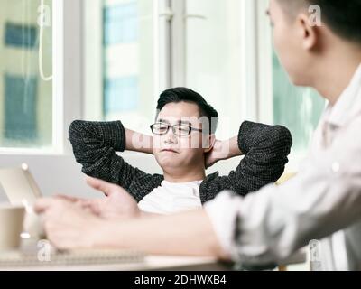 two young asian entrepreneurs discussing business in office using digital tablet Stock Photo