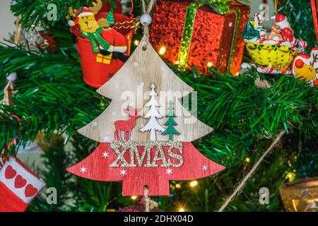 Advent Feast festive Christmas wooden decoration with Xmas sign. Seasonal colorful composition figure before decorated lit green tree. Stock Photo