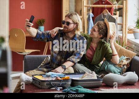Young couple posing in sunglasses and in hat on mobile phone making selfie portrait before journey Stock Photo
