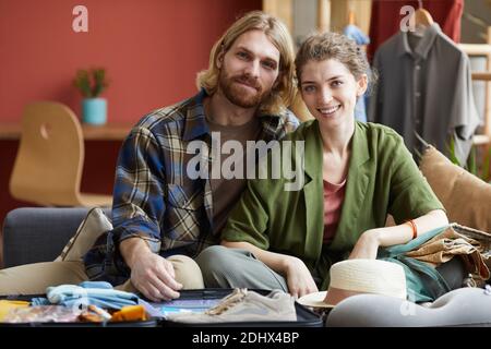 Portrait of young happy couple sitting on sofa together and smiling at camera at home Stock Photo