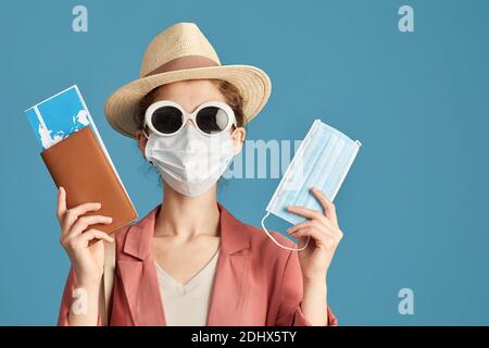 Portrait of young woman in mask and in sunglasses posing at camera with tickets and masks Stock Photo