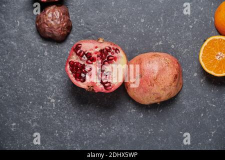 Close up of colorful pomegranate with orange and passion fruit on dark grey stone background. Healthy and fresh fruits for boosting vitamin C Stock Photo