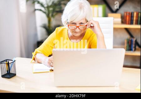 Senior woman is using laptop for work indoor Stock Photo
