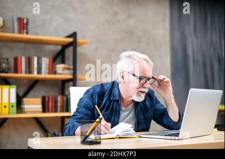 Older man using laptop for studying, working Stock Photo